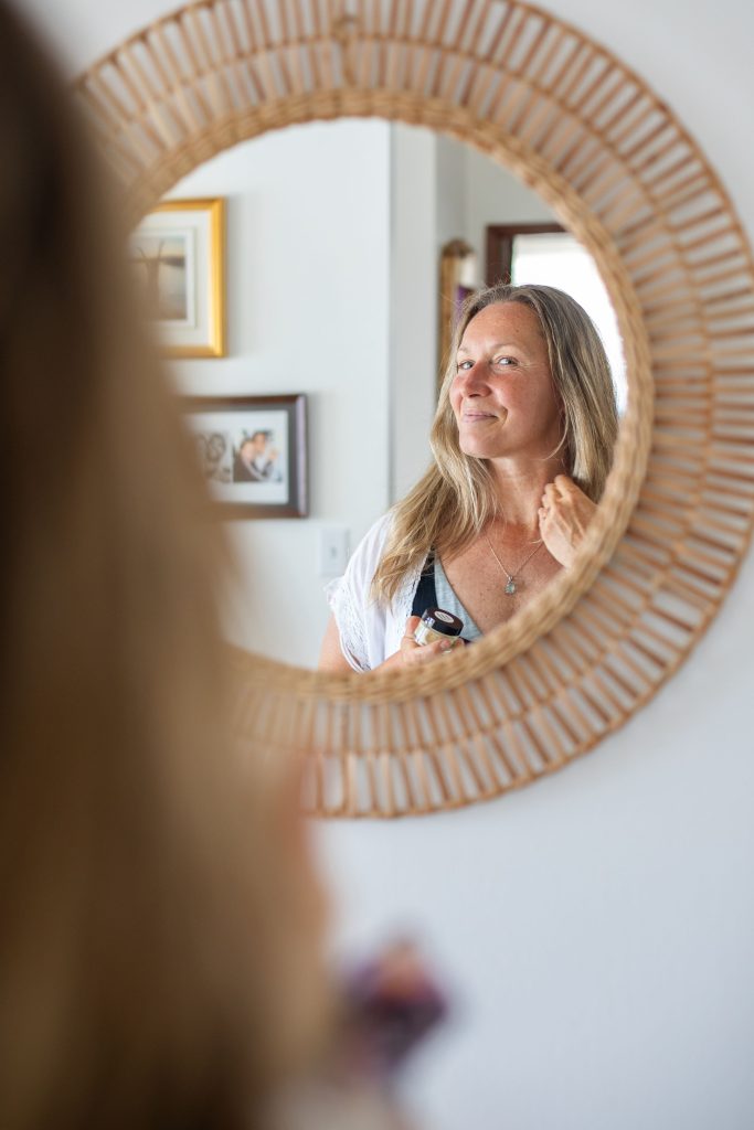 Livia smiling at reflection in the mirror while using her face cream